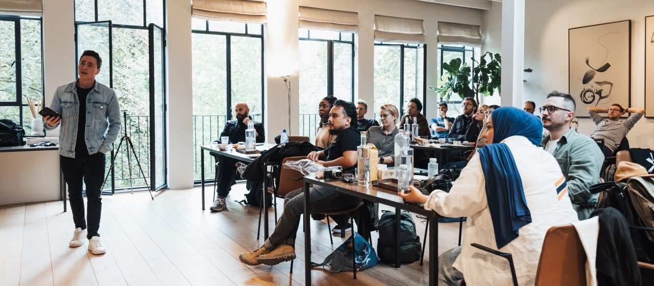 Diverse group attending workshop, focused on speaker presenting in modern indoor setting.
